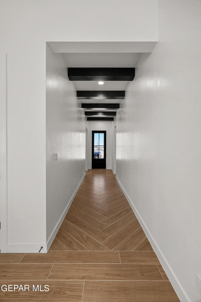 corridor with wood tiled floor, baseboards, and beamed ceiling