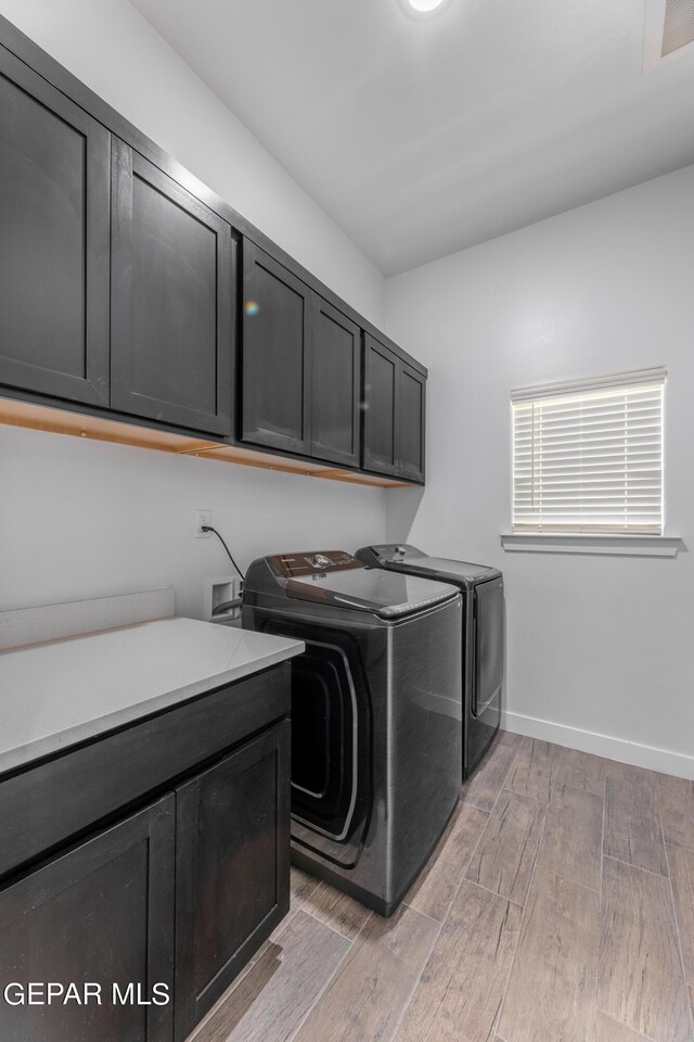 laundry room featuring cabinets, light wood-type flooring, and washing machine and dryer