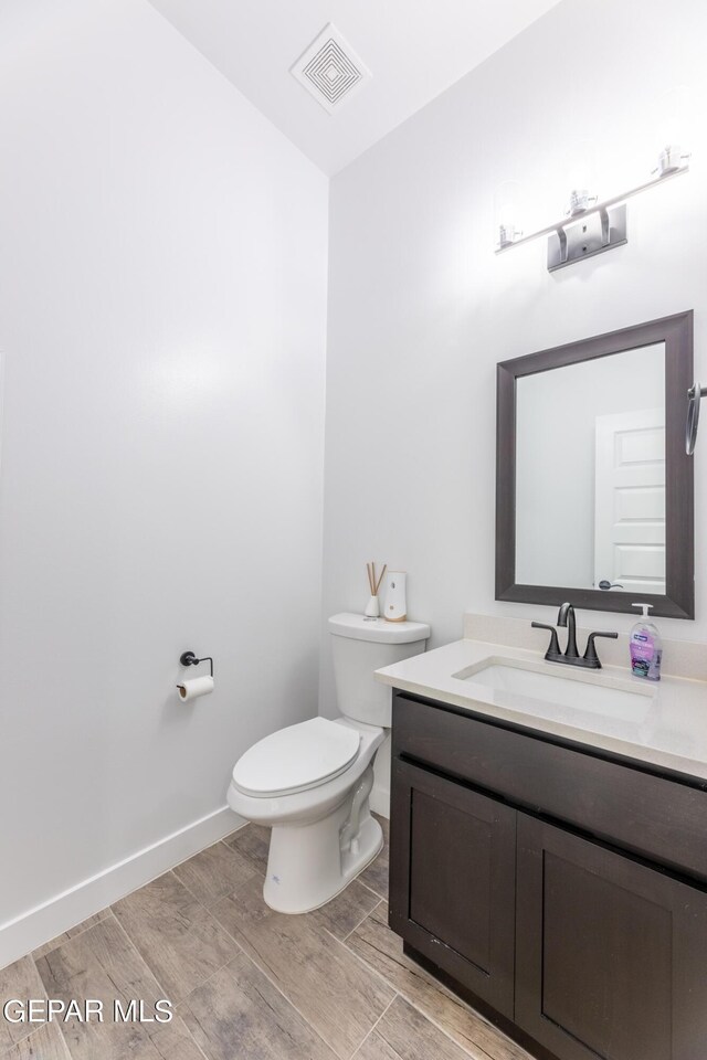 bathroom with hardwood / wood-style floors, toilet, and vanity