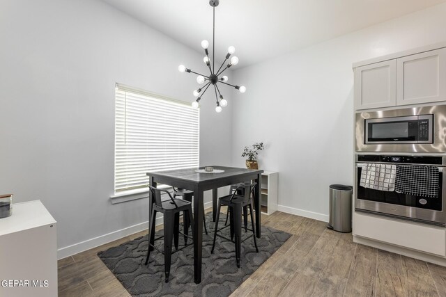 dining area featuring lofted ceiling, plenty of natural light, dark hardwood / wood-style floors, and a notable chandelier