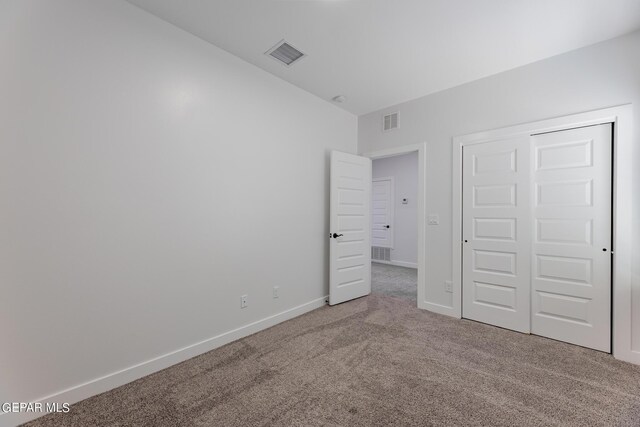 unfurnished bedroom featuring light colored carpet and a closet