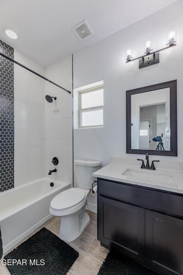 full bathroom featuring tiled shower / bath, toilet, and vanity