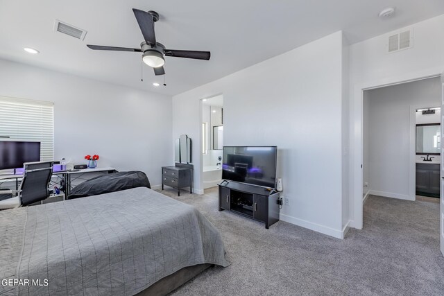 bedroom with ceiling fan, light colored carpet, and ensuite bath