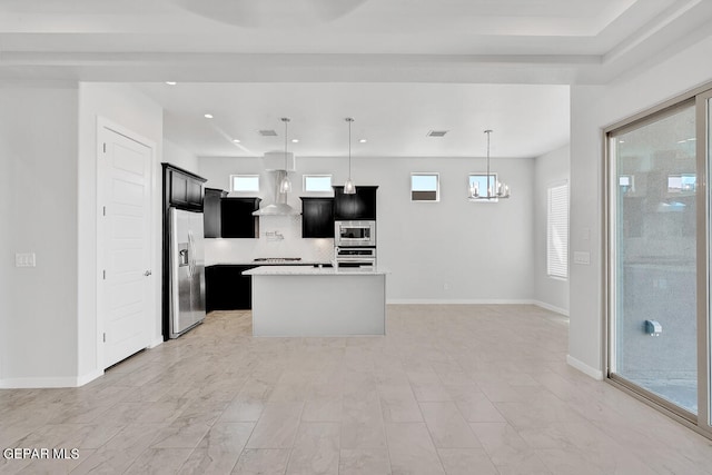 kitchen featuring appliances with stainless steel finishes, plenty of natural light, an island with sink, and wall chimney exhaust hood