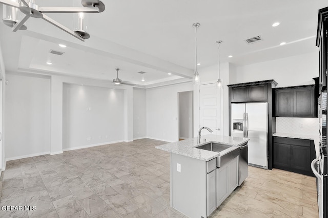 kitchen with light tile patterned floors, sink, a center island with sink, and a tray ceiling