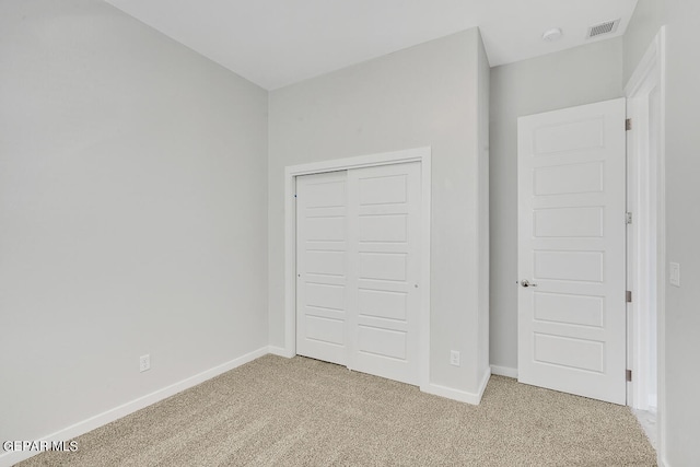 unfurnished bedroom with a closet and light carpet