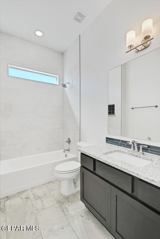 full bathroom with tile patterned flooring, tiled shower / bath, toilet, and vanity