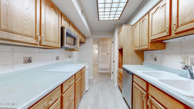 kitchen with light hardwood / wood-style flooring, stainless steel appliances, sink, and backsplash