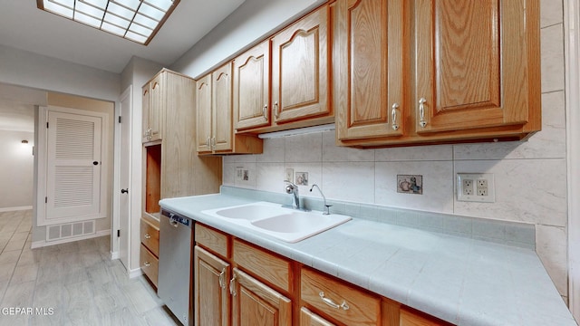 kitchen with a sink, visible vents, baseboards, decorative backsplash, and dishwasher