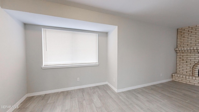 unfurnished room featuring a fireplace, wood finished floors, and baseboards