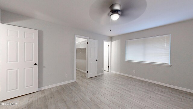 unfurnished bedroom with light hardwood / wood-style flooring, ceiling fan, a spacious closet, and a closet