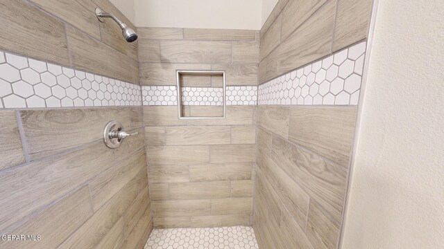 bathroom with a tile shower and tile patterned flooring