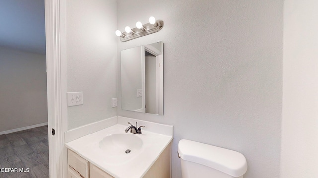 half bath featuring toilet, wood finished floors, and vanity