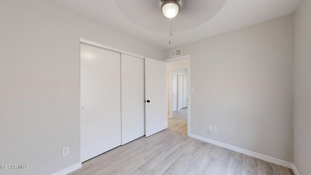 unfurnished bedroom featuring light wood-type flooring, a closet, and ceiling fan