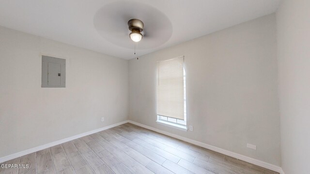 empty room with light hardwood / wood-style flooring, electric panel, and ceiling fan