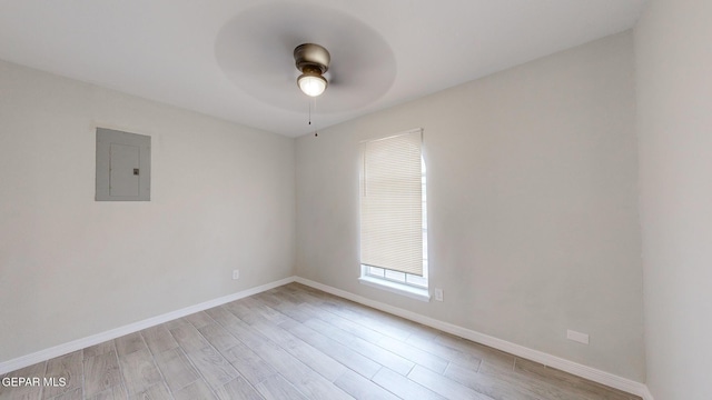 unfurnished room with a ceiling fan, electric panel, light wood-style flooring, and baseboards