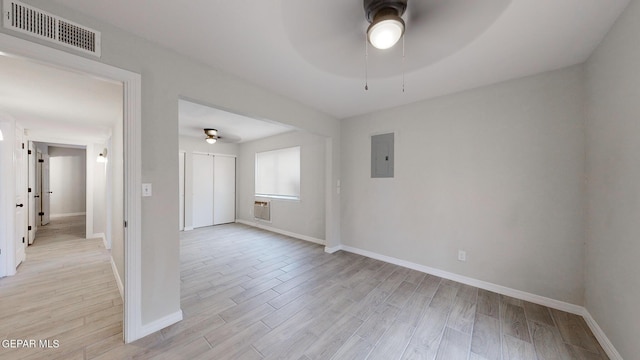 empty room with light wood-style flooring, electric panel, visible vents, and ceiling fan