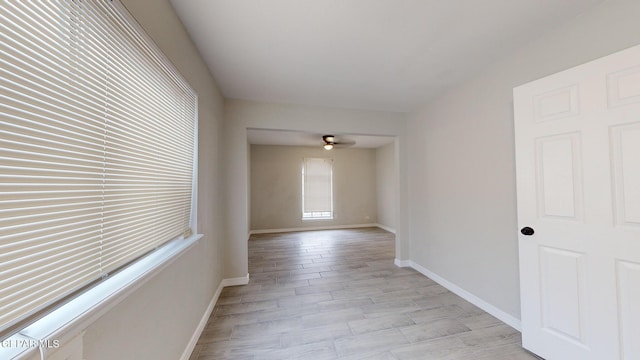 spare room featuring light wood-type flooring, baseboards, and a ceiling fan