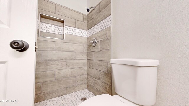 bathroom with toilet and a tile shower