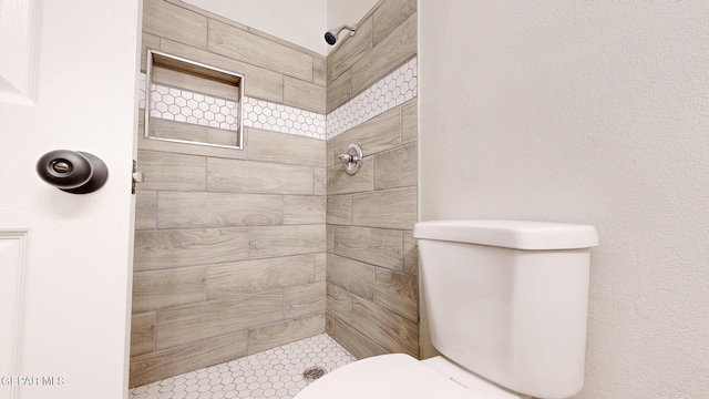 bathroom featuring tiled shower and toilet