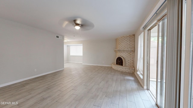 unfurnished living room with baseboards, visible vents, a ceiling fan, light wood-style floors, and a fireplace