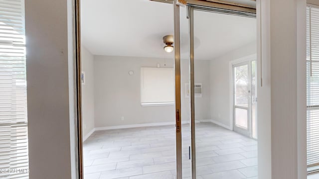 unfurnished room with ceiling fan, baseboards, and a wall mounted AC