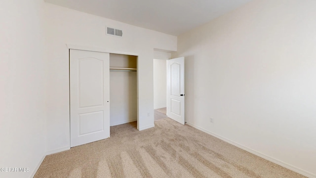 unfurnished bedroom featuring light carpet and a closet