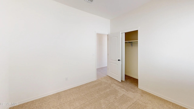 unfurnished bedroom featuring a closet and light colored carpet