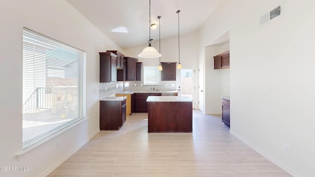 kitchen featuring tasteful backsplash, dark brown cabinets, a kitchen island, vaulted ceiling, and pendant lighting