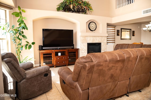 living room with a high ceiling, light tile patterned flooring, visible vents, and a tile fireplace