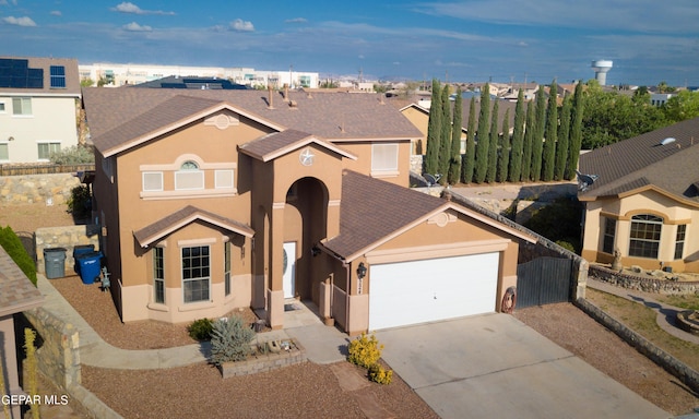 view of front facade featuring stucco siding, an attached garage, driveway, and fence