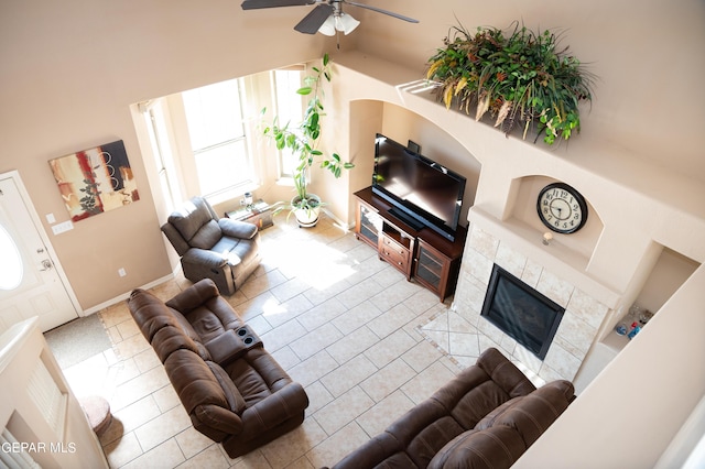 living room with ceiling fan, baseboards, tile patterned flooring, and a tile fireplace