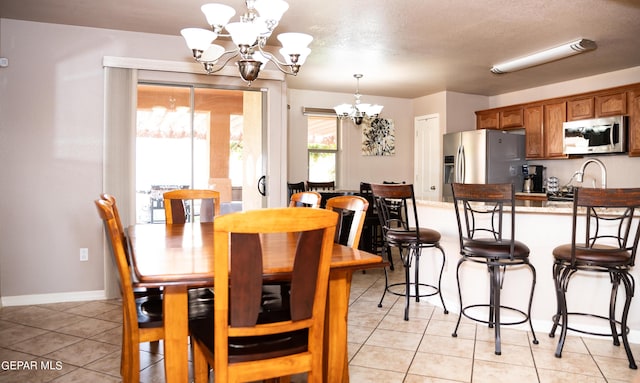 dining area featuring light tile patterned flooring, baseboards, a textured ceiling, and an inviting chandelier