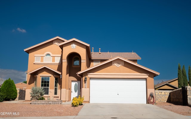 view of front of home with stucco siding, driveway, an attached garage, and fence