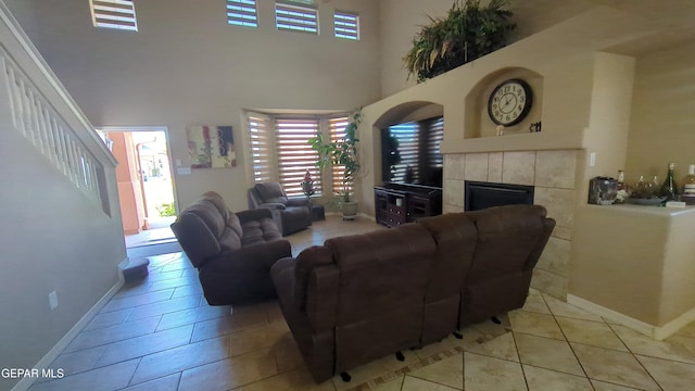 living room with baseboards, a high ceiling, light tile patterned flooring, and a fireplace