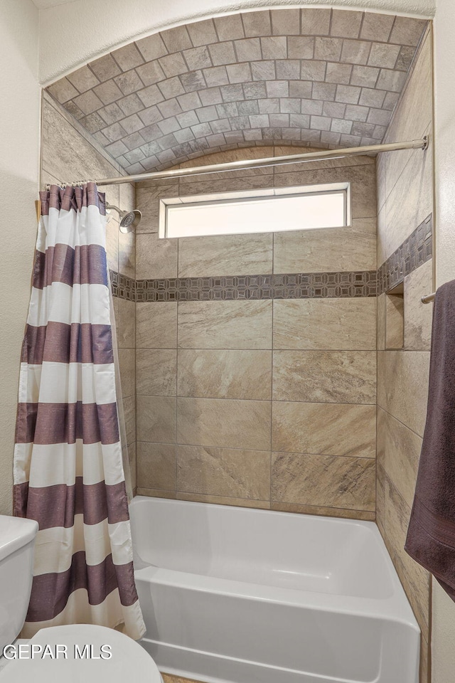 bathroom featuring toilet and shower / bathtub combination with curtain