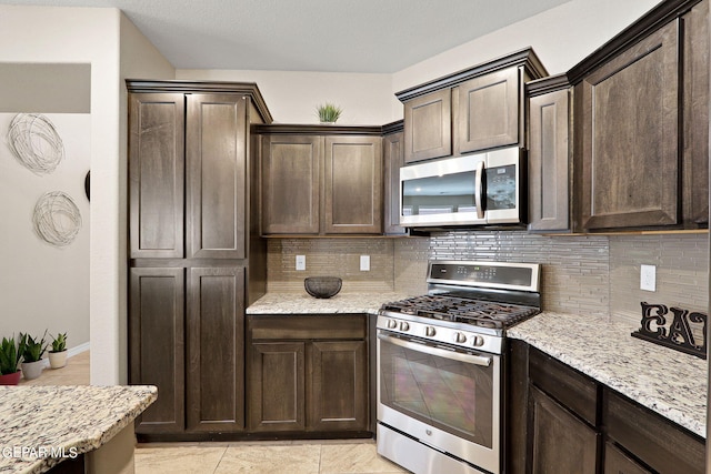 kitchen featuring tasteful backsplash, appliances with stainless steel finishes, light stone counters, and dark brown cabinetry