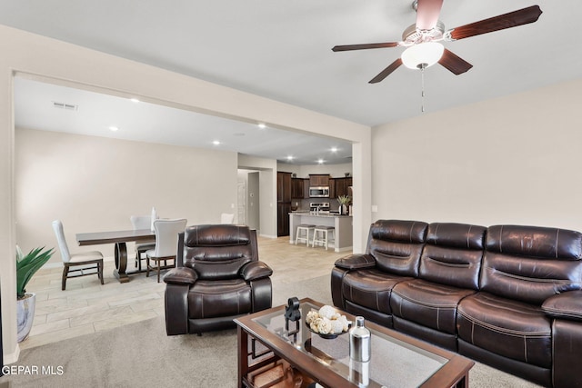 living room with ceiling fan and light colored carpet