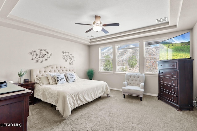 carpeted bedroom with a tray ceiling and ceiling fan