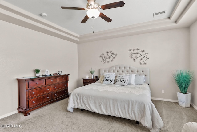 carpeted bedroom featuring a raised ceiling and ceiling fan