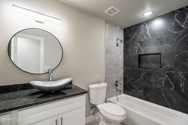 full bathroom featuring tiled shower / bath combo, toilet, and vanity