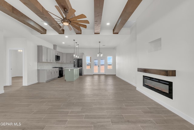 1385 Syrian Desert Dr, Chaparral, NM 88081 - unfurnished living room with a glass covered fireplace, beamed ceiling, a ceiling fan, light wood-style floors, and recessed lighting