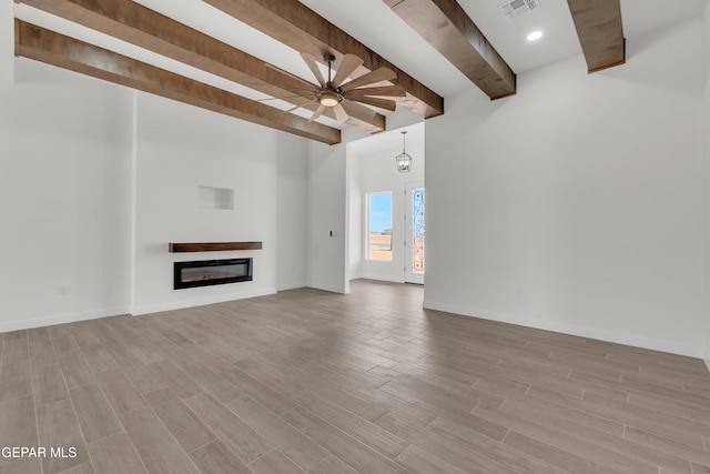 1385 Syrian Desert Dr, Chaparral, NM 88081 - unfurnished living room featuring beam ceiling, ceiling fan, a glass covered fireplace, and light wood-style floors