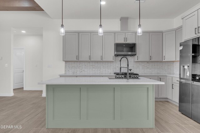 1385 Syrian Desert Dr, Chaparral, NM 88081 - kitchen with stainless steel refrigerator with ice dispenser, decorative backsplash, a kitchen island with sink, light wood-style flooring, and hanging light fixtures