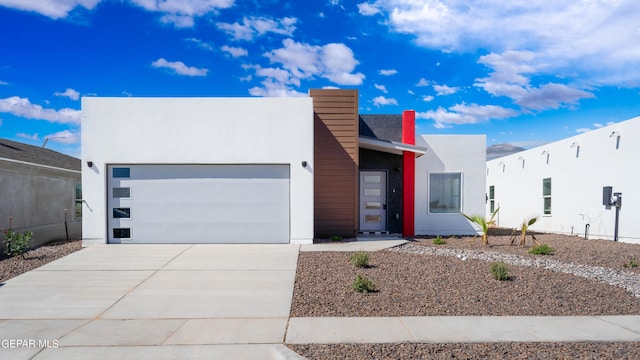 contemporary home featuring driveway, an attached garage, and stucco siding