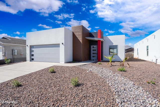 modern home featuring concrete driveway, an attached garage, and stucco siding