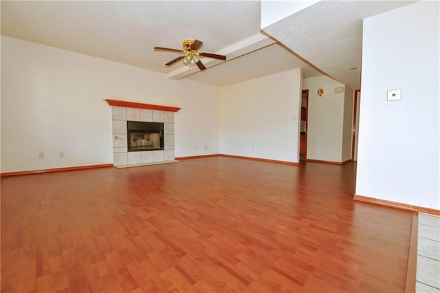 unfurnished living room with a textured ceiling, ceiling fan, a tile fireplace, and hardwood / wood-style flooring