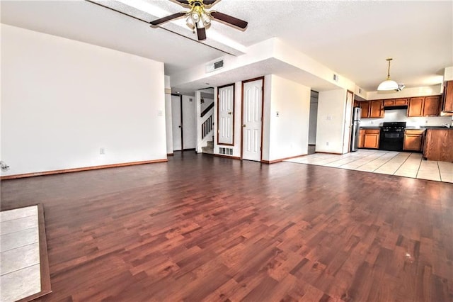 unfurnished living room with ceiling fan, a textured ceiling, and light hardwood / wood-style flooring