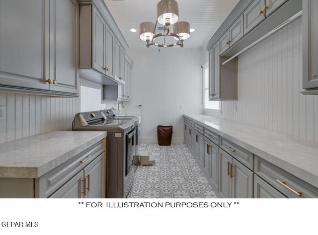 laundry area with washer and dryer, cabinets, wood walls, and a chandelier