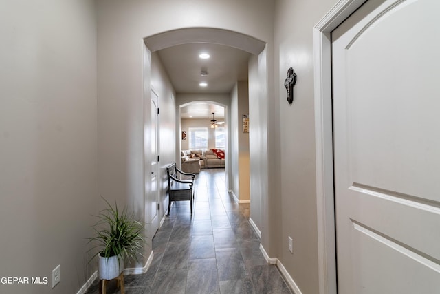 hallway featuring baseboards, arched walkways, and recessed lighting